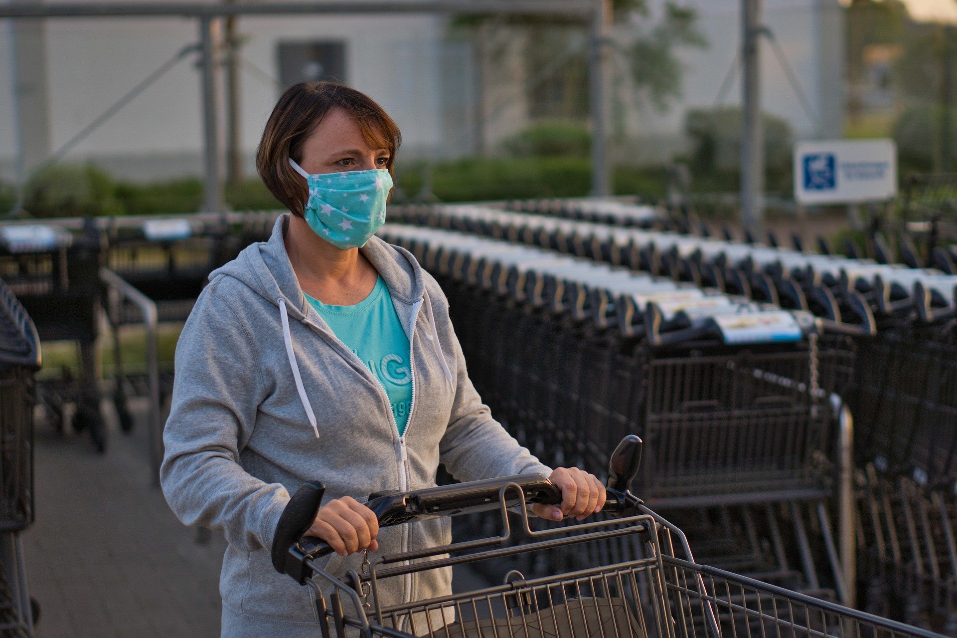 Vrouw met mondkapje en winkelwagen