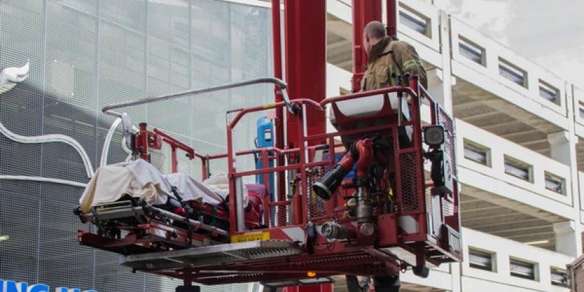 Ambulancemedewerkers met patient vast in lift