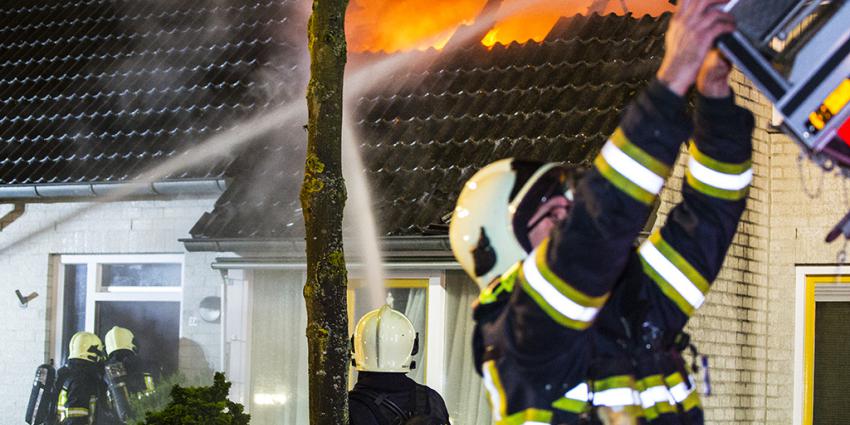 Vlammen slaan uit dak woning