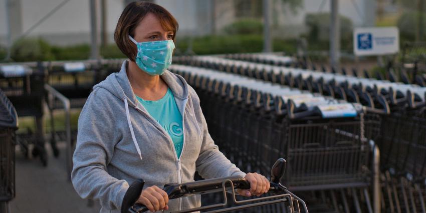 Vrouw met mondkapje en winkelwagen