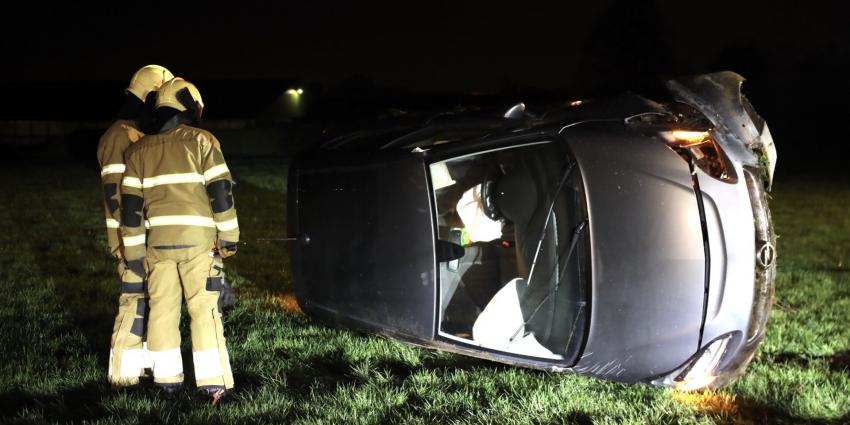 Auto op zijn kant in weiland