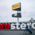 Greenpeace klimmers met spandoek op reclamezuil Schiphol Plaza