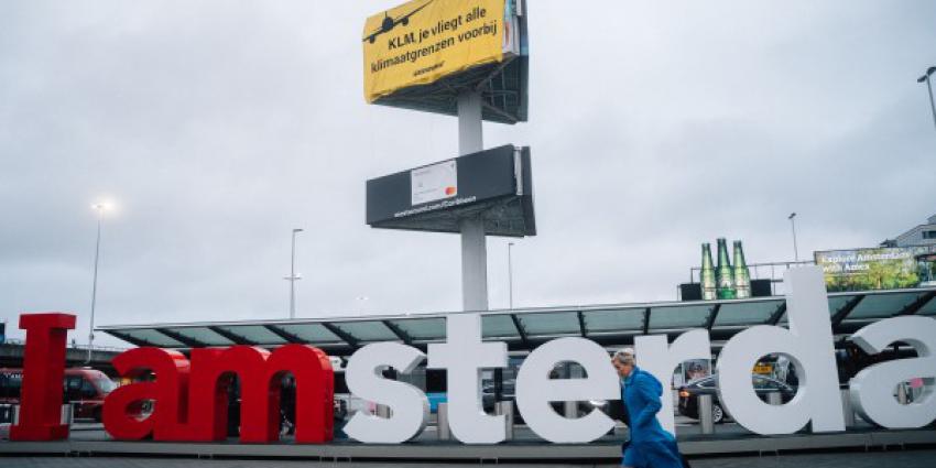 Greenpeace klimmers met spandoek op reclamezuil Schiphol Plaza
