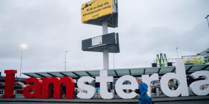 Greenpeace klimmers met spandoek op reclamezuil Schiphol Plaza