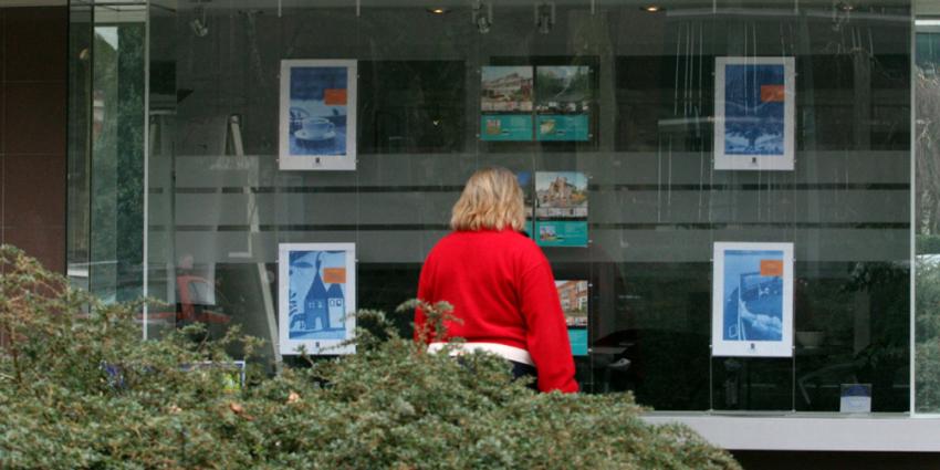 Vrouw bekijkt woningen in etalage