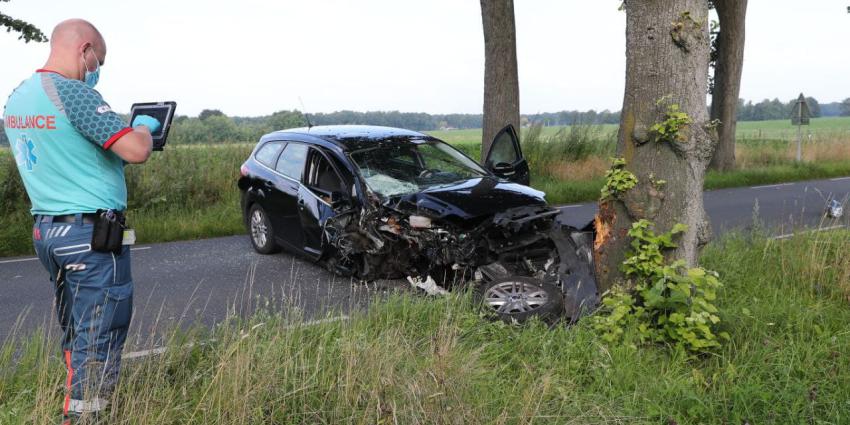 Ambulancemedewerker neemt foto van gecrashte auto 