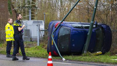 Auto op zijn kant tegen lantaarnpaal
