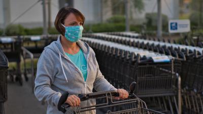 Vrouw met mondkapje en winkelwagen