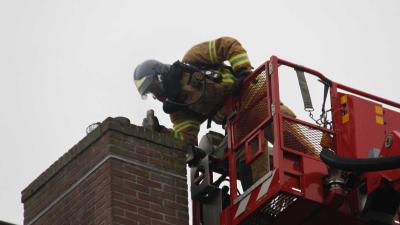 Brandweerman bezig met schoorsteenbrand