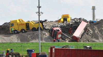 Vrachtwagen valt van puinberg bij afvalverwerker